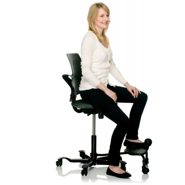 Side view of employee sitting in HAG Capisco saddle seat with step