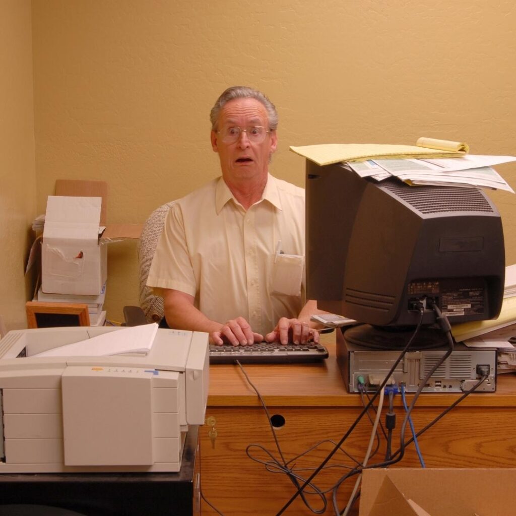 Stressed out man at computer with messy desk
